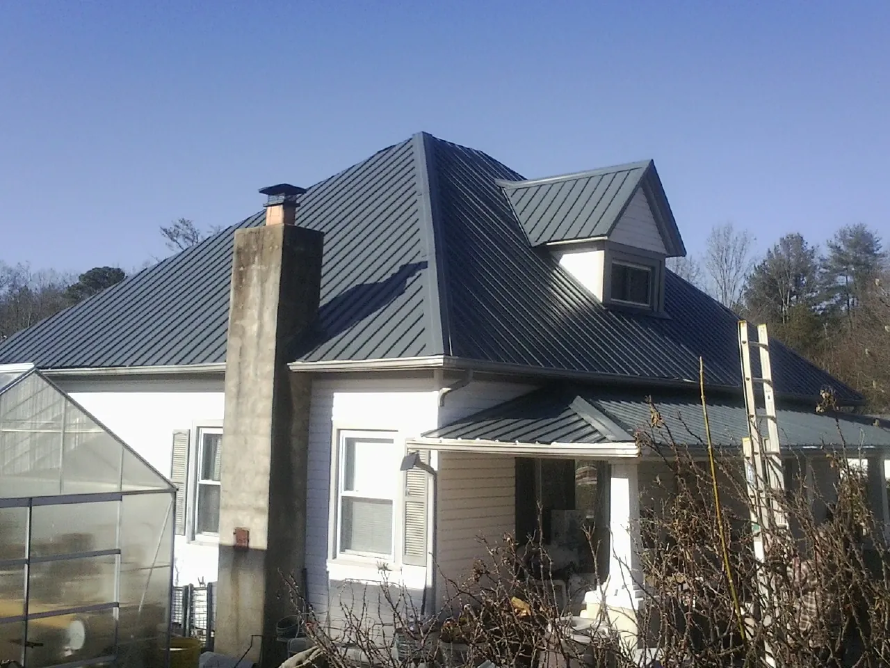 Dark blue standing seam metal roof on a white farmhouse with dormer — Slate & Tile Roof Repair by Roofing Brothers in Mohawk