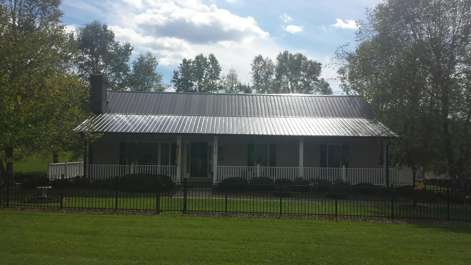 Gray metal roof on a brick ranch with a full width front porch — Gutter Guard Installation work by our crew in Mohawk