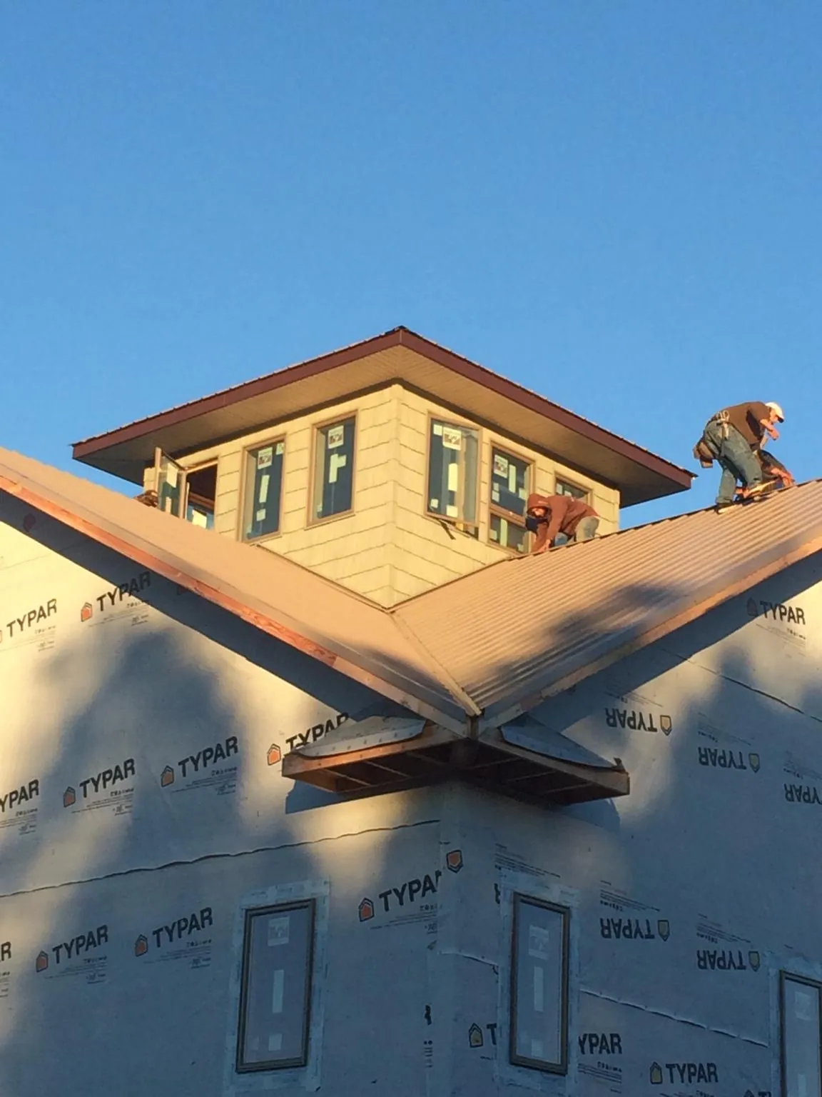 Roofers working around a rooftop cupola on a new metal roof at sunset — Roof Waterproofing in Mohawk by Roofing Brothers